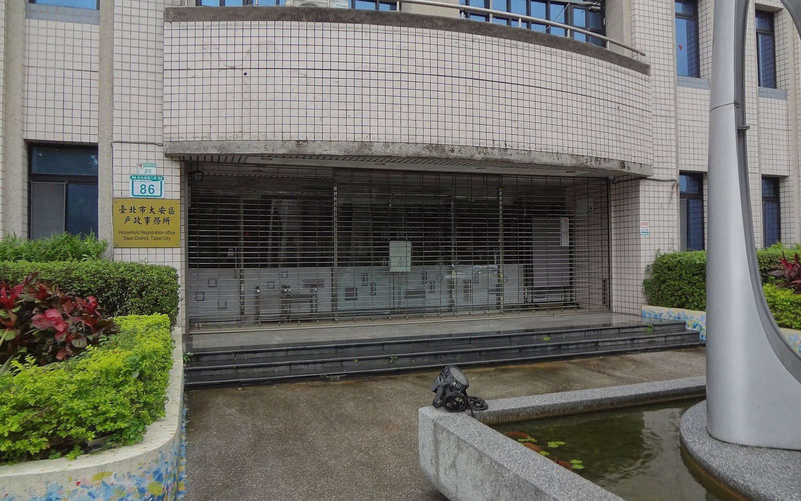 Curved tiled entrance of the Daan District household registration office with a shuttered storefront