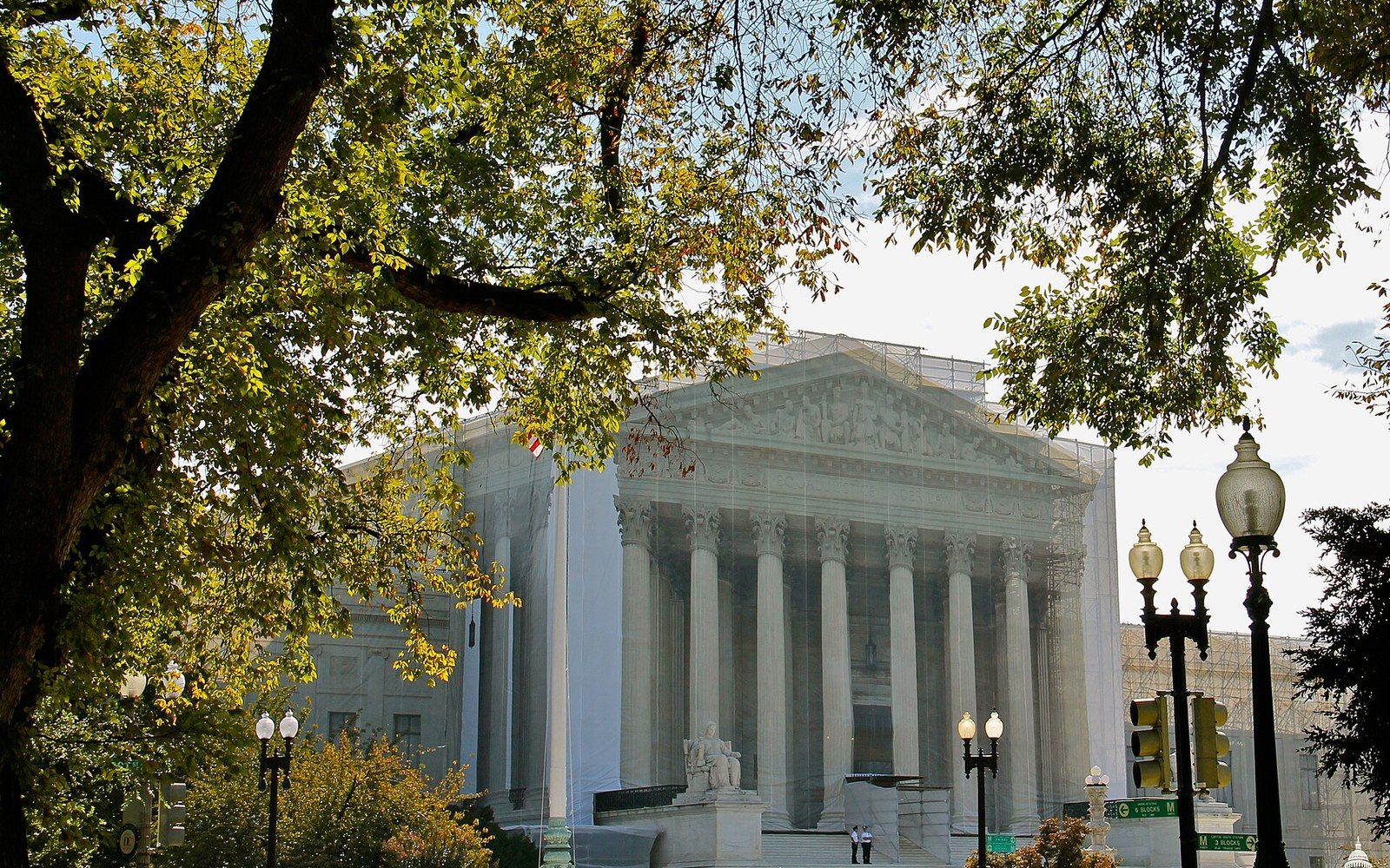 The Supreme Court building's columned facade seen through tree branches and streetlamps