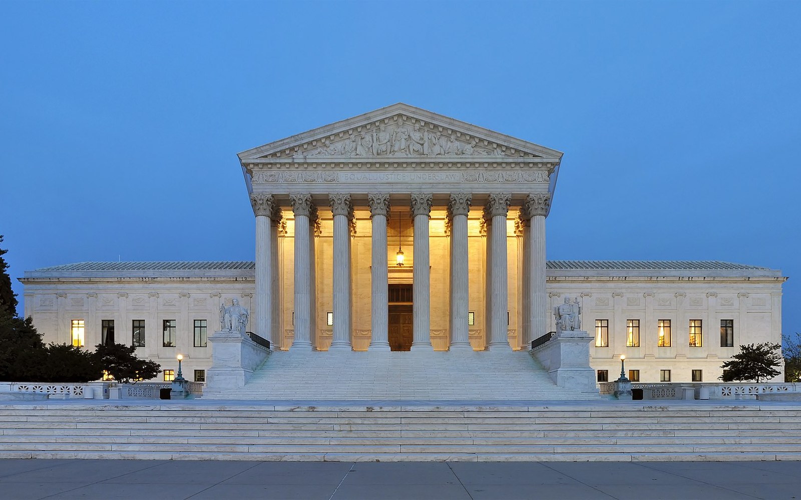 The west facade of the United States Supreme Court building, shot square-on in flat daylight, the marble steps and 'Equal Justice Under Law' inscription visible